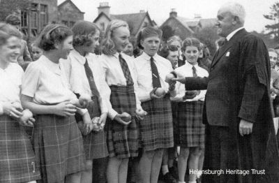 Dance group
A 1951 image of members of gym teacher John Blain's Dance Group, receiving apples sent from British Columbia. Pictured (from left) are Judith Peel, Pat Paterson, Jean Hamilton, Lexine Milne, Hazel Russel, Joyce Henderson (the head between Hazel and Sheena), Sheena Campbell, teacher James Bell and Sonja Aitken. Image supplied by Sheena Campbell's elder brother, Iain G.Campbell, who now lives in Canada.
