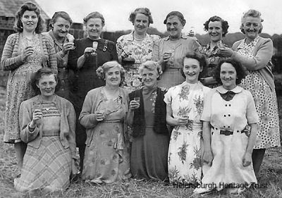 Farm ladies party
A FORMER Helensburgh woman now living in Shetland, Cathy Shearer, is trying to find out more about this photo of a group of women, including her granny, Barbara McAdam (back row 5th from left), who died in 1954 aged 67. The photo was taken between 1940-1954 by Alexandria photographers Leddy and Glen, probably in the Helensburgh area. At the time Barbara lived at either Callendoune Farm, Helensburgh, or Crossburn Cottage half a mile from the Cross Keys towards Luss. She would like to find out where and when the photo was taken, who the group of women are and what the occasion is. If you can help, please email the editor of this website.
