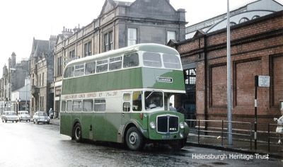 A green Garelochhead Coach Services Regent bus is pictured on a rainy day outside Helensburgh Central Station. Image, date unknown,Â© A.Murray-Rust licensed for reuse under Creative Commons Licence.
