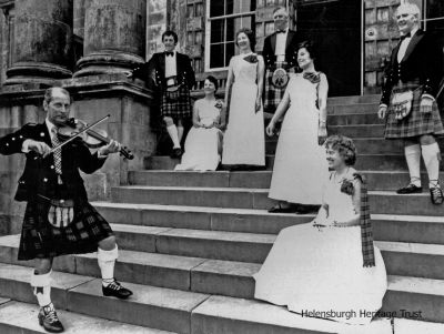 TV demonstration
Helensburgh and district members of the Royal Scottish Dance Society gave a demonstration at Rossdhu House, Luss, ancestral home of the Clan Colquhoun and now the Loch Lomond Golf Club clubhouse, for BBC programme "Great Britons â€” Robert Burns" in 1977. The violinist was Jimmy Yeaman, and the dancers from left were Bob Drummond, Etta Rennie, Mary McIntosh, George Rennie, Peggy Rose, Joyce Gregor and Ken Sharp. Image supplied by Anne Thorn.

