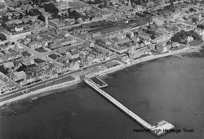 Helensburgh town centre
An aerial view of the pier and the town centre, showing the outdoor swimming pool, the Old Parish Church, the Central Station and the railway goods yard. The image, date unknown, is from the collection of William Orr of Rhu, who was at one time the Burgh Engineer before becoming the Assistant Engineer for Argyllshire, and it was supplied by his great nephew, Alistair Quinlan.
