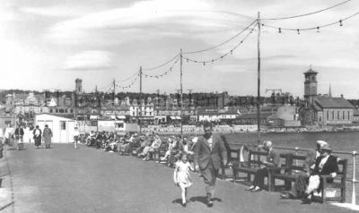 Helensburgh Pier
A sunny day on the pier, with coloured lights running the length of the pier. Date unknown. From the image collection of the late Nan Moir, of Cove.
