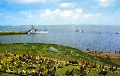 Landing craft
One of the Landing Craft which used to ply from Rhu to Benbecula is pictured moored at Helensburgh pier, while crowds on the seafront take advantage of the evening sunshine. Image circa 1973.
