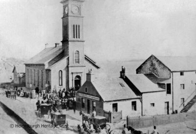 Old Parish Church
Parishioners arrive for a service at the Old Parish Church on the seafront. Next door is the Granary, at that time run by R.S.McFarlane & Son, Grain Merchants. Image, date unknown, supplied by Malcolm LeMay.
