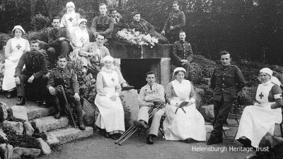 At the Wishing Well
During World War One from 1914-18 the Helensburgh Town Council-owned Hermitage House in Hermitage Park became a military hospital with a capacity for 58 patients who were sent from Stobhall Hospital in Glasgow. The wounded men in their blue uniforms were a familiar sight in the town, being wheeled around the park by their nurses. A number of local ladies and girls helped out in the hospital and the local Red Cross detachment also assisted the trained nurses. Here some of the patients and staff are seen posing beside the Wishing Well in Hermitage Park. Image date unknown.
