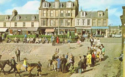 Seafront pony rides
Rides on ponies and donkeys on Helensburgh seafront used to be very popular in summer. The image date is unknown, but the shops behind are a tobacconist, T.G.Allan Ltd., Leathar & Co., and D.H.Davidson Ltd.
