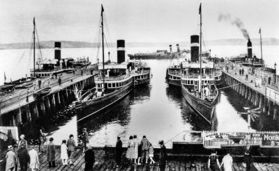 Steamers at Craigendoran
A 1933 picture of most of the LNER fleet at Craigendoran. The two which can be seen least well are the Lucy Ashton and the Jeanie Deans, while in the centre are the Talisman and the Marmion. The steamer terminal and station opened for business under the North British Railway on May 15 1882, and steamer services were finally withdrawn in 1972. The piers have since become derelict, and on the firth side of the line the station buildings are long gone.
