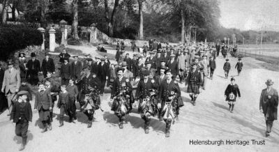 Marching to Rhu
The Helensburgh Citizen Training Force marches past Pier Road, Rhu, led by members of the Helensburgh Clan Colquhoun Pipe Band, during World War One. Image supplied by Eric McArthur who suspects the gentleman on the grass verge with the black suit and black hat and walking stick could be his grandfather, Alexander Macarthur, who lived at 56 John Street. The object of the Citizen Training Force was to provide military training for men ineligible for business or other valid reasons to enlist in the Forces.
Keywords: Parade to Rhu