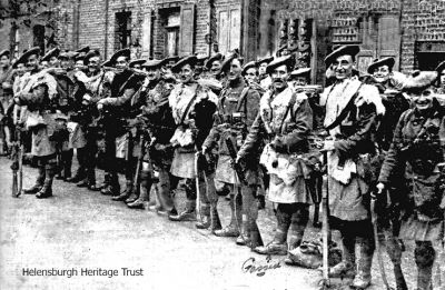 Going to war
Local soldiers leaving for World War One. The second and third soldiers in, who have a kit bag between them, both have gassed written next to them. On the back of the original photo was written: 2nd on left back row - killed; soldier in front row 6th from left with dark bear skin over his shoulders - wounded; soldier behind him to the right - prisoner; soldier with a moustache in front of door - prisoner. More details would be welcomed. Copy image supplied by Liz Sutherland.
